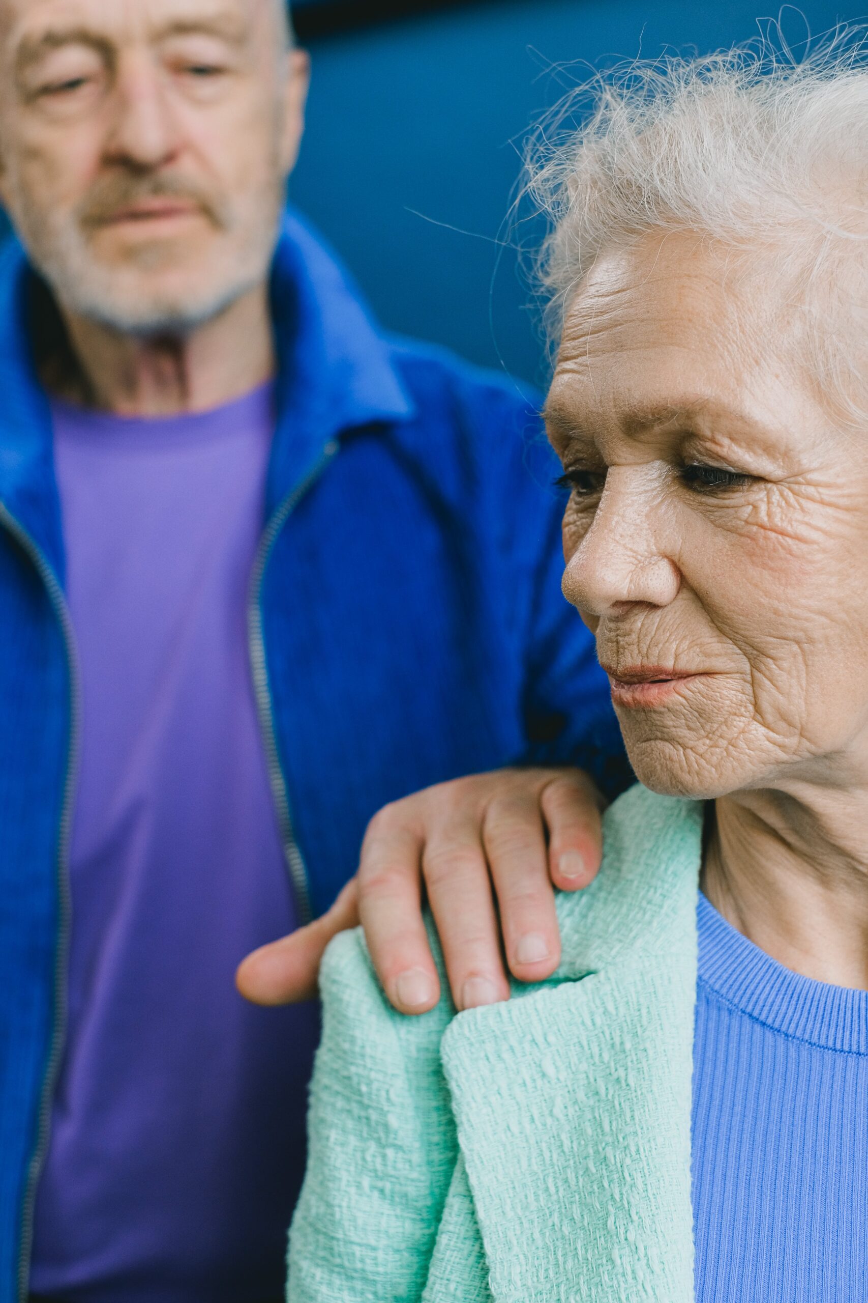Elderly man with hand on shoulder of elderly woman